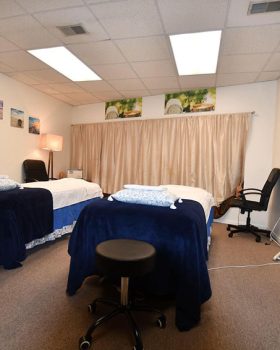 A serene massage room featuring two massage beds and comfortable chairs