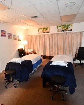 A serene massage room featuring two comfortable chairs and a central table