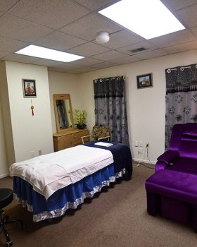 A serene massage room featuring purple chairs and a desk