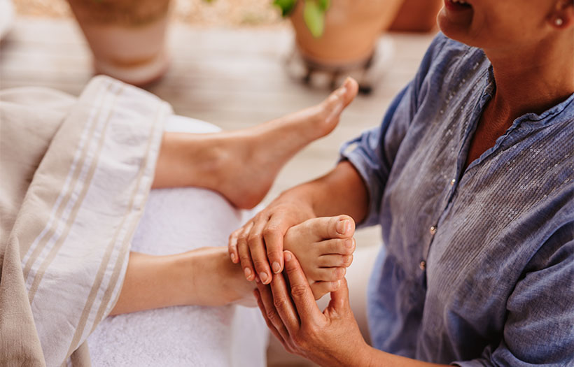 A person relaxing in bed while receiving a soothing foot massage