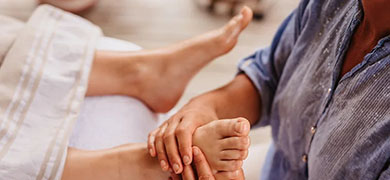 A person relaxing in bed while receiving a soothing foot massage